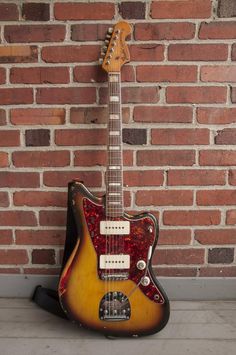 an electric guitar sitting against a brick wall