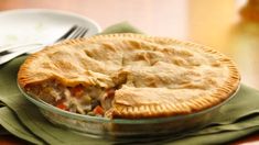 a close up of a pie on a table with a plate and fork in the background