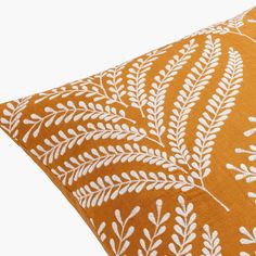 an orange pillow with white leaves on it