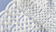 white woven material is displayed on a blue surface, with an intricate design in the center