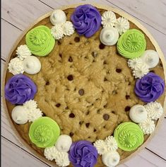 a cookie cake decorated with purple, green and white icing