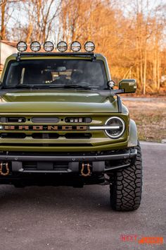 the front end of a green truck with lights on it's headlamps