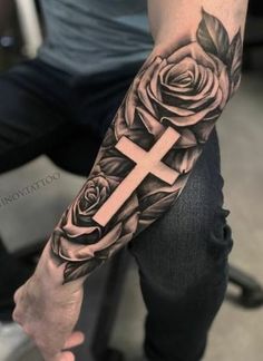 a man with a cross and roses tattoo on his arm