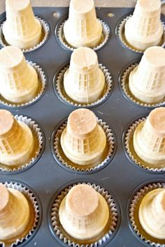 cupcakes with white frosting in a muffin tin lined with paper cups