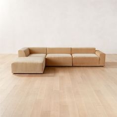 a couch sitting on top of a hard wood floor next to a white wall in an empty room