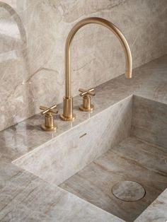 two faucets on the side of a sink in a marbled bathroom area