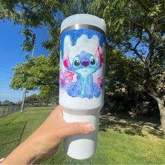 someone is holding up a water bottle with an image of stitching on it in the grass