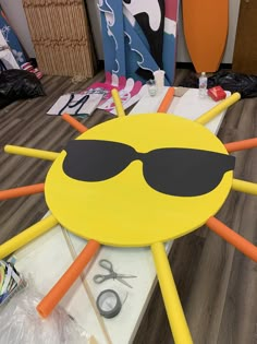 a yellow table topped with sunglasses and orange sticks