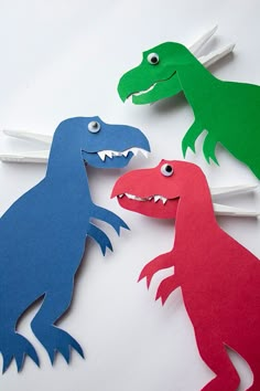 three paper dinosaurs with toothpicks in their mouths