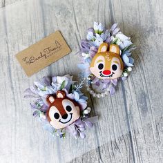 two brooches with flowers on them sitting on a table