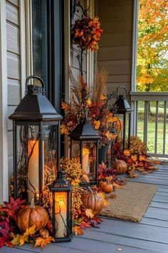 some lanterns are sitting on the porch with fall leaves and pumpkins around them,