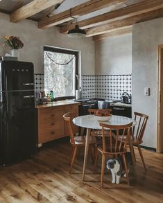 a kitchen with wooden floors and an old fashioned refrigerator in the corner, next to a dining room table