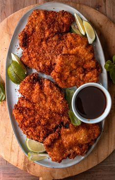 fried chicken on a plate with dipping sauce and lime wedges next to the side