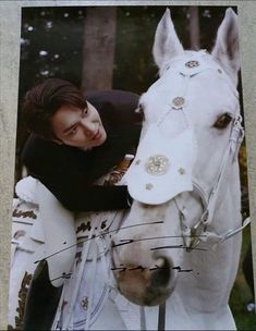 a woman standing next to a white horse