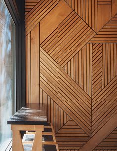 a wooden bench sitting in front of a window next to a wall with geometric designs on it