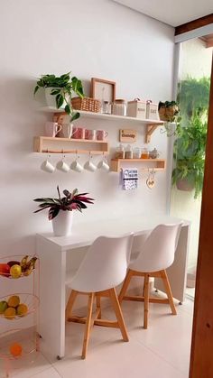 a dining room table with chairs and shelves on the wall above it, along with potted plants