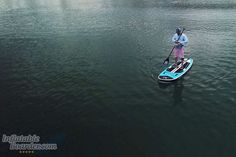 a man standing on top of a paddle boat in the middle of a body of water