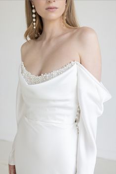 a woman in a white dress with pearls on her shoulder