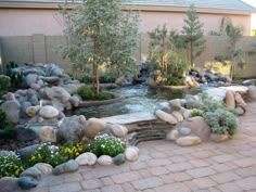 a garden with rocks and plants in the center, along with a pond surrounded by stones