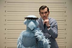 a man in a suit and tie standing next to a sesame character