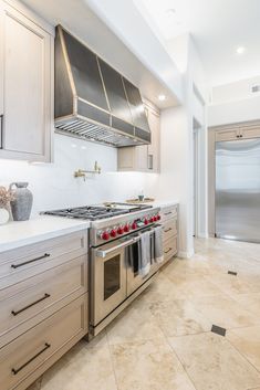 a large kitchen with stainless steel appliances and marble counter tops, along with beige cabinets