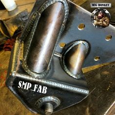 a metal object sitting on top of a piece of wood with the words smp fab below it