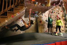 two people are climbing up the side of a rock wall while another person is standing next to them