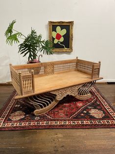 a wooden bench sitting on top of a rug next to a painting and potted plant