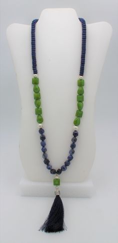 "Long Sodalite star-cut stone necklace, with tropical green Czech glass accent beads,  blue wood and silver-plated \"lava\" beads. A long blue silk tassel  provides a colorful focal point. This is a really pretty necklace as the blue and green  both compliment  each other nicely.  This is an attention-getting necklace." Red Jade Bracelet, Long Tassel Necklace, Graduation Necklace, Pretty Necklace, Blue Beaded Necklace, Tropical Green, Lava Beads, Fabric Necklace, Stone Beaded Necklace