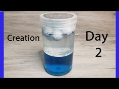 a glass filled with blue liquid sitting on top of a wooden table next to the words creation day 2