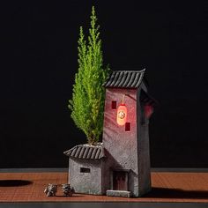 a small house with a tree growing out of it's roof and the light on