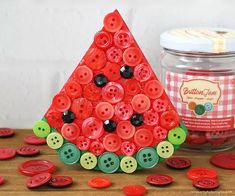 a red and green christmas tree made out of buttons on a wooden table next to a jar of jelly beans