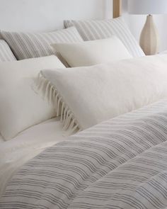 a bed with white and grey striped pillows