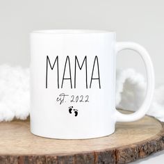 a white coffee mug with the word mama printed on it sitting on a wood slice