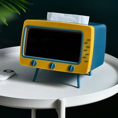 a yellow and blue tv sitting on top of a white table next to a remote control