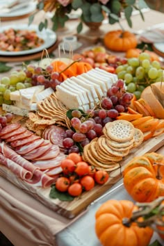 an assortment of cheeses, crackers and fruits on a table