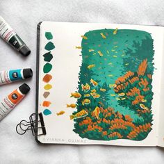 an open book with watercolors and markers next to it