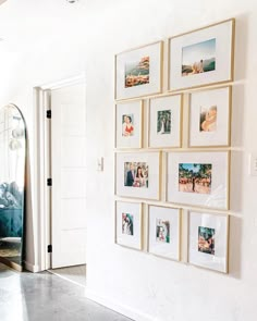 a white wall with pictures hanging on it and a mirror in front of the door