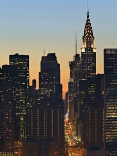 the city skyline is lit up at night, with skyscrapers in the foreground