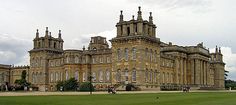 the large building has many windows and towers on it's sides, along with people walking around