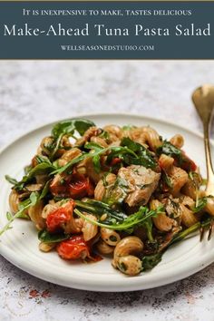 a white plate topped with pasta and spinach