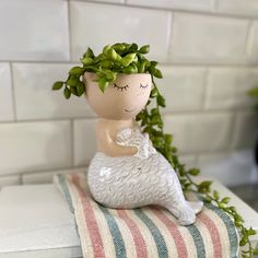 a ceramic figurine sitting on top of a towel next to a potted plant