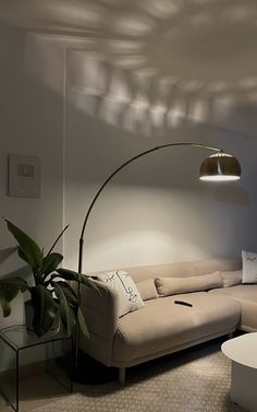 a living room with a couch, table and floor lamp in front of the window