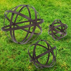 three metal balls sitting on top of green grass