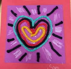 a heart made out of rope on top of a piece of pink paper with black writing