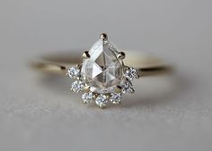 an engagement ring with a pear shaped diamond surrounded by smaller diamonds