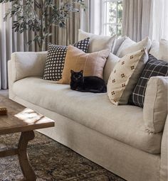 a living room with a couch, coffee table and large window covered in drapes