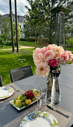 the table is set with flowers and fruit on it, along with plates and silverware