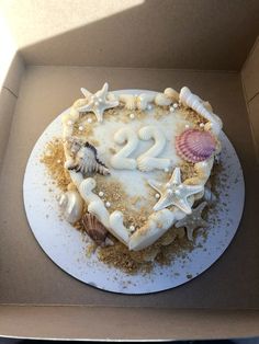 a heart shaped cake with seashells and starfish on it in a box