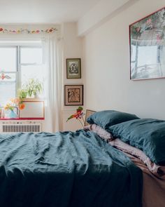 an unmade bed sitting in front of a window next to a radiator